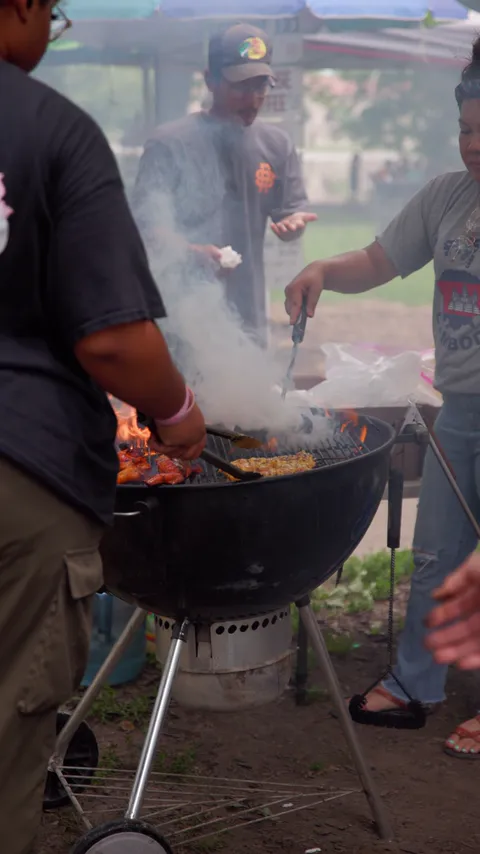 People cooking food on an outdoor barbecue