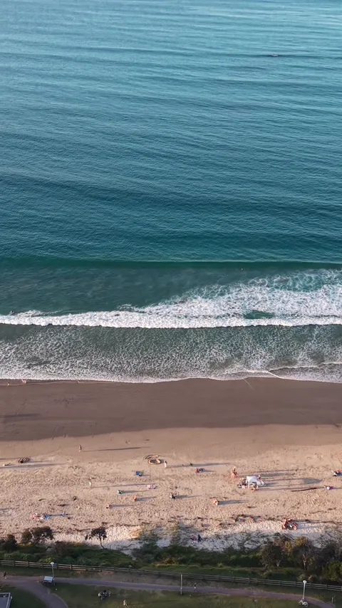 Aerial view of waves rolling onto a long sandy beach at Byron Bay