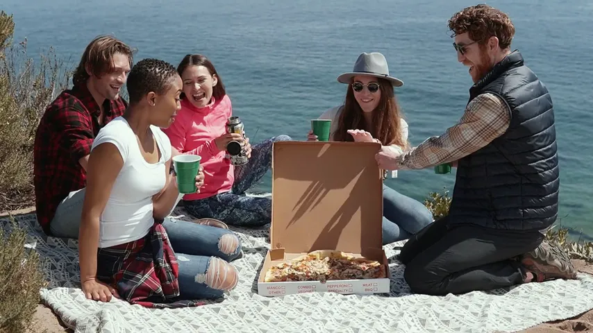 Friends laughing together at a picnic by the sea