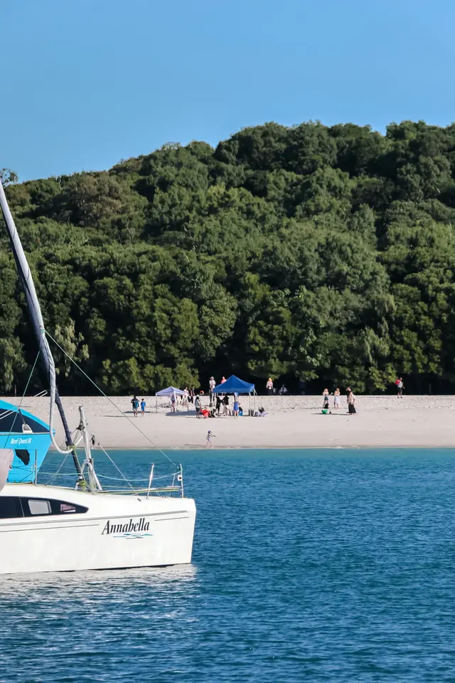 A sailboat anchored off a white sand beach in the Whitsundays